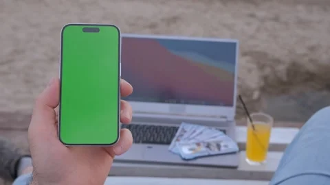 Man's hands use smartphone with laptop, money dollars on the beach closeup, top Stock Footage 246319815