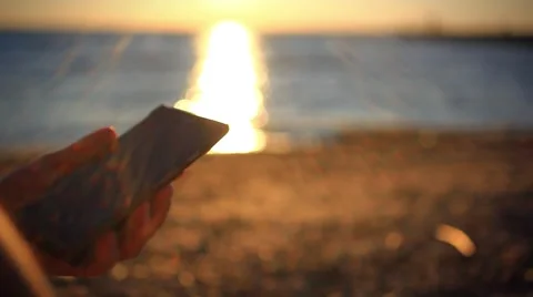Man's hands uses mobile smartphone near the sea at sunset beach. With blurred Stock Footage 51720861