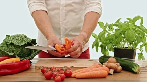 The man's hands using a kitchen knife cutting the sweet peppers on the wooden Stock-Footage 201139933