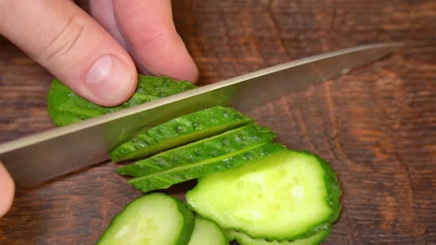 Man's hands using a kitchen knife cut fresh cucumber on cutting board Stock Footage 254079639