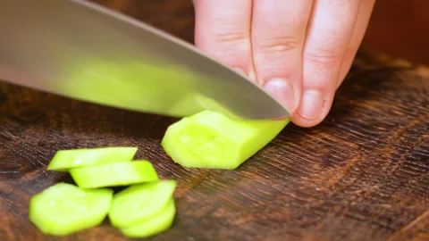 Man's hands using a kitchen knife cut fresh cucumber on cutting board Stock Footage 254594629