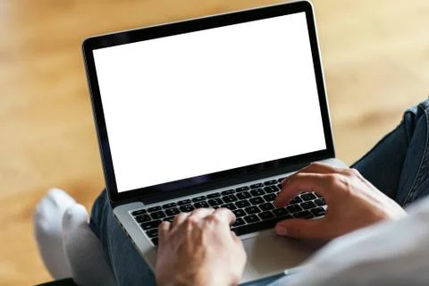 Man's hands using laptop with blank screen on desk in home interior. Work con Stock Photos