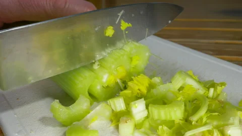 Mans hands using a large knife to chop some sticks of raw celery. Stock-Footage 165556517