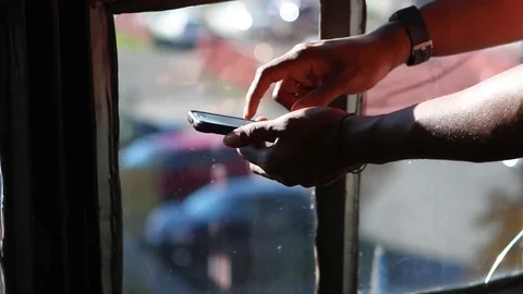 Man's Hands Using Mobile Device Against Weathered Window Stock Footage 83017130