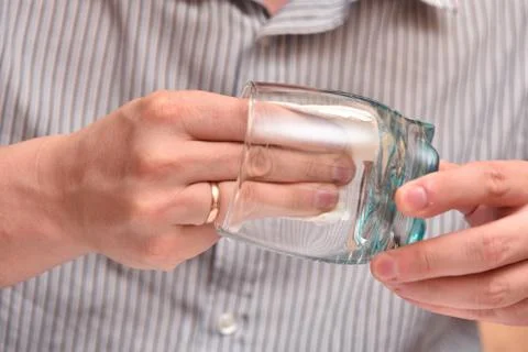 Man's hands, using a napkin, wipe a transparent glass for drinking so that th Stock Photos