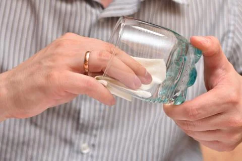 Man's hands, using a napkin, wipe a transparent glass for drinking so that th Foto stock