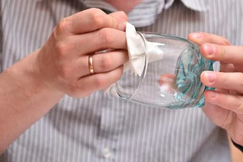 Man's hands, using a napkin, wipe a transparent glass for drinking so that th Stock Photos
