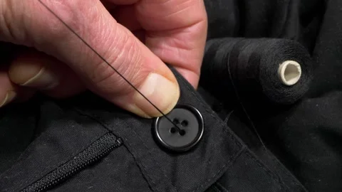 A man’s hands using needle and thread to sew a button onto a garment. Vídeos de archivo 292160872