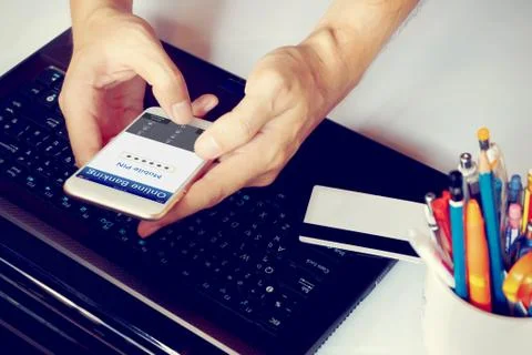 Man's hands using online banking and pressing PIN number with smartphone on.. Stock Photos