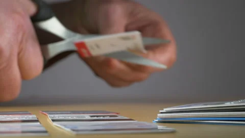 Man's hands using scissors to cut a plastic card from a pile in half. Video stock 146599512