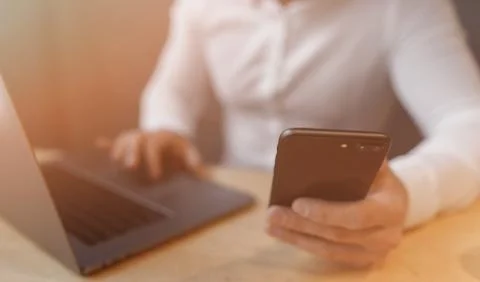 Man's hands using smart phone and laptop in interior. Foto stock