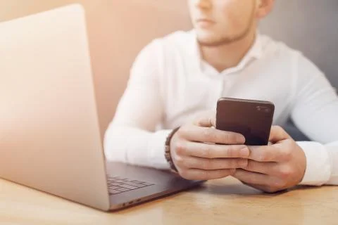 Man's hands using smart phone and laptop in interior. Stock Photos