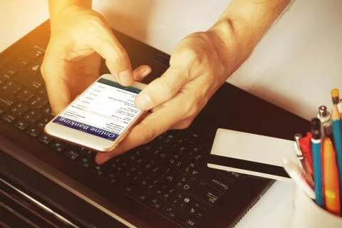 Man's hands using smartphone for online banking on the desk in the office o.. Stock Photos