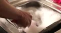 Mans hands washing up porcelain teapot in sink in kitchen with loads of foam HD Footage