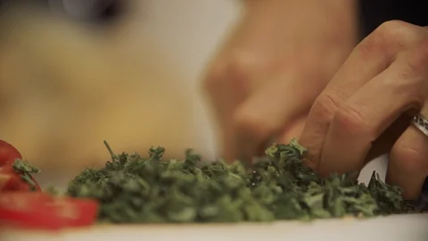 Man's hands wearing wedding ring cuts into fresh parsley veggies with a knife. Stock Footage 99937581