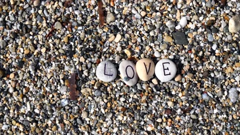 Man's hands will lay out the word love from sea stones with letters Stock Footage 138751104