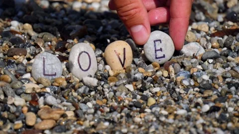 Man's hands will lay out the word love from sea stones with letters Stock Footage 138752038