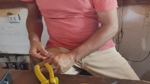 Man's hands at a workbench carefully crafting with golden grass wire spool. Stock Footage 312897646