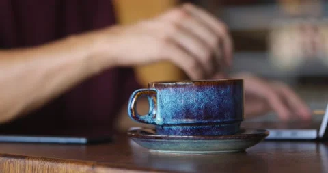 Man's hands working on laptop while sitting in a coffee shop. Waitress bringing Stock Footage 163996543