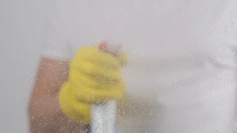 Man's hands in yellow rubber gloves wipes cleaning detergent and wiper a window. Stock-Footage 129248968