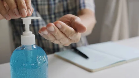 Man's handwriting in a notebook and using alcohol gel to wash his hands. 動画素材 128885952