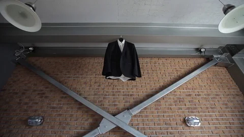 A man's jacket and suit hangs on a hanger near a red brick wall before the groom Stock Footage 93841032