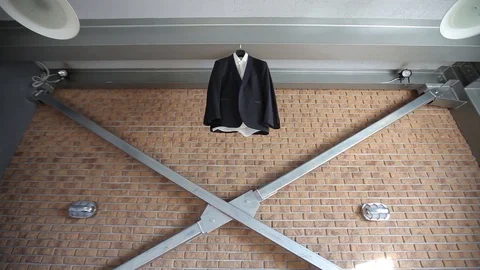 A man's jacket and suit hangs on a hanger near a red brick wall before the groom 스톡 동영상 93841075