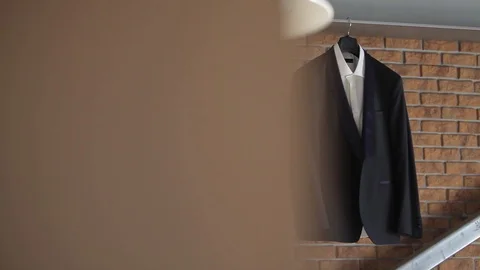 A man's jacket and suit hangs on a hanger before the groom's wedding Stock Footage 93841669