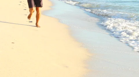 Man's legs are seen jogging on beach Stock Footage 61930285