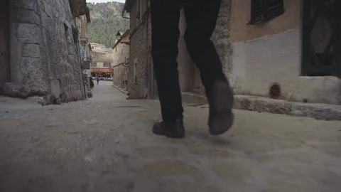 Man's legs are walking on the cobblestone street of medieval village Valdemossa Stock Footage 83864167