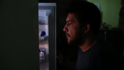 A mans open a fridge door in complete darkness in the middle of the night Vídeos de archivo 145037652