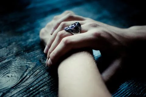 Man's pale hands with laying on the black wooden table. Skull (Reaper) ring Stock Photos