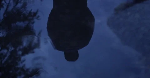 Man's reflection on a puddle of water with raindrops falling down 動画素材 76051871