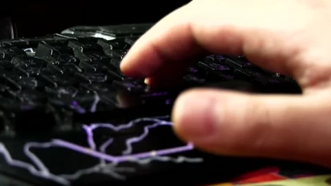 A man's right hand fingers typing on a black, illuminated keyboard Stock Footage 342256195