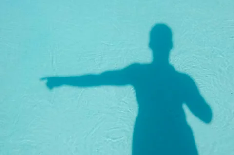 Man's shadow in blue pool pointing Foto stock