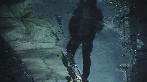 Man's shadow is reflected in puddle Stock Footage 90664966