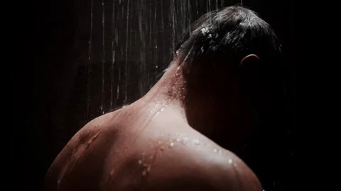 A mans silhouette in a refreshing shower creates a relaxing scene with flowing Stock-Footage 306917664