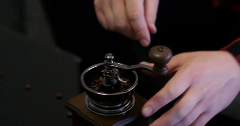  Man's strong hands with red and black squared shirt grinding coffee Stock Footage 104407920