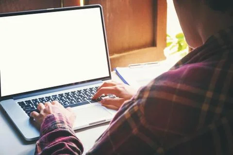 Man's using laptop with blank screen on desk in home interior. Stock Photos