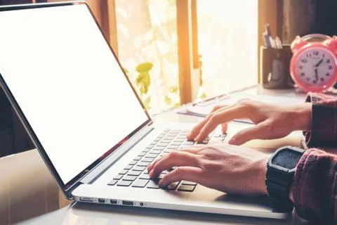 Man's using laptop with blank screen on desk in home interior. Business conce Stock Photos