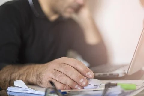 A man's using laptop hand on mouse and thinks Stock Photos