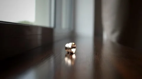 Man's wedding ring rolls across the wooden table to a woman's wedding ring. Stock Footage 255295688