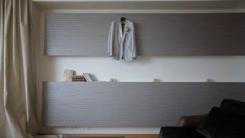 A man's white jacket and suit hangs on a hanger before the groom's wedding 動画素材 93850650