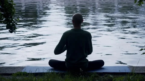 Man's yogi in the background of water simulates the tension of the bow string Stock Footage 136945044