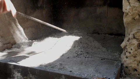 Manual Ash Removal and Leveling in Rustic Stone Oven with Long Metal Tool Stock Footage 336526663