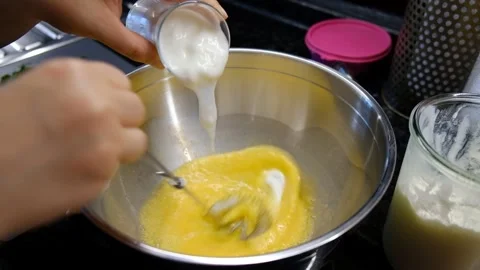 Manual Egg Beating in Deep Bowl with Cream Added While Mixing – Cooking Stock Footage 302687348