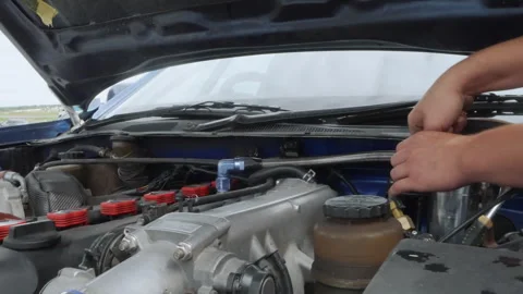 Manual engine adjustment using screwdriver under vehicle hood. Closeup of Stock Footage 341972634