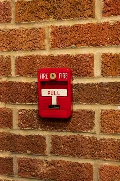 Manual fire alarm activation pull station on masonry wall Stock Photos