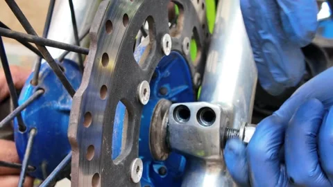 Manual labor Torqueing Motorcycle Axle Bolt on Custom blue Hub Stock Footage 320938244