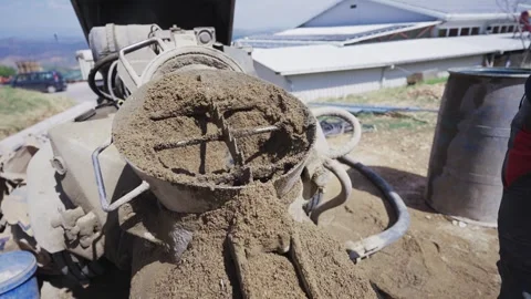 Manual sand adding into rotating cement mixer with freshly mixed concrete spi Stock Footage 303181496